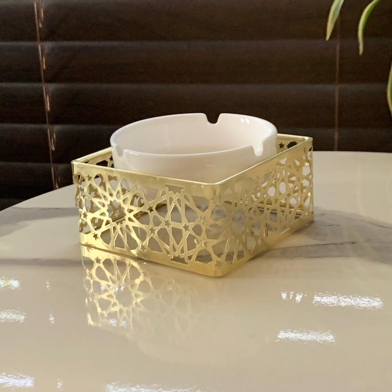 a gold ashtray on a marble table