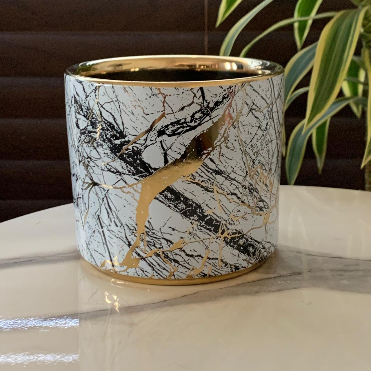 a white and gold pot on a marble table