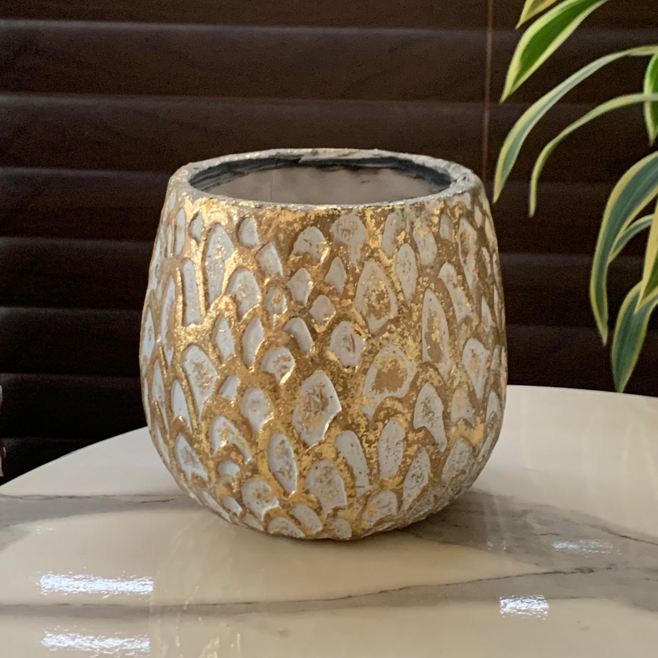a gold and white vase on a marble table