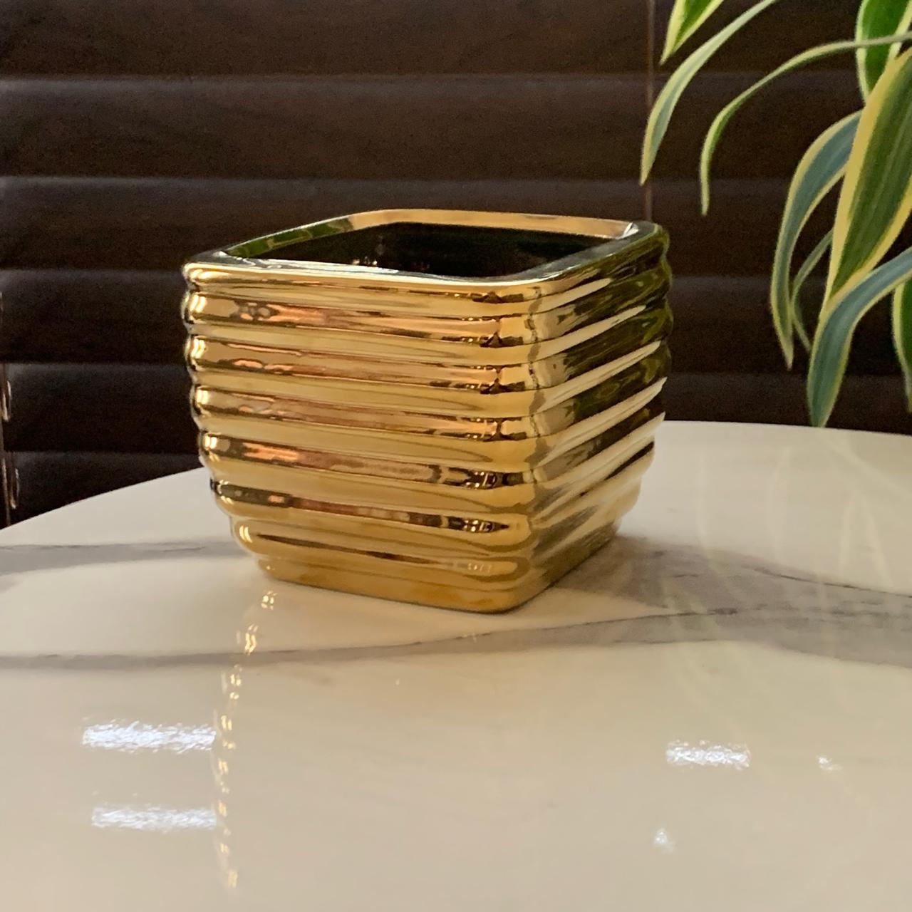 a gold square pot on a marble table