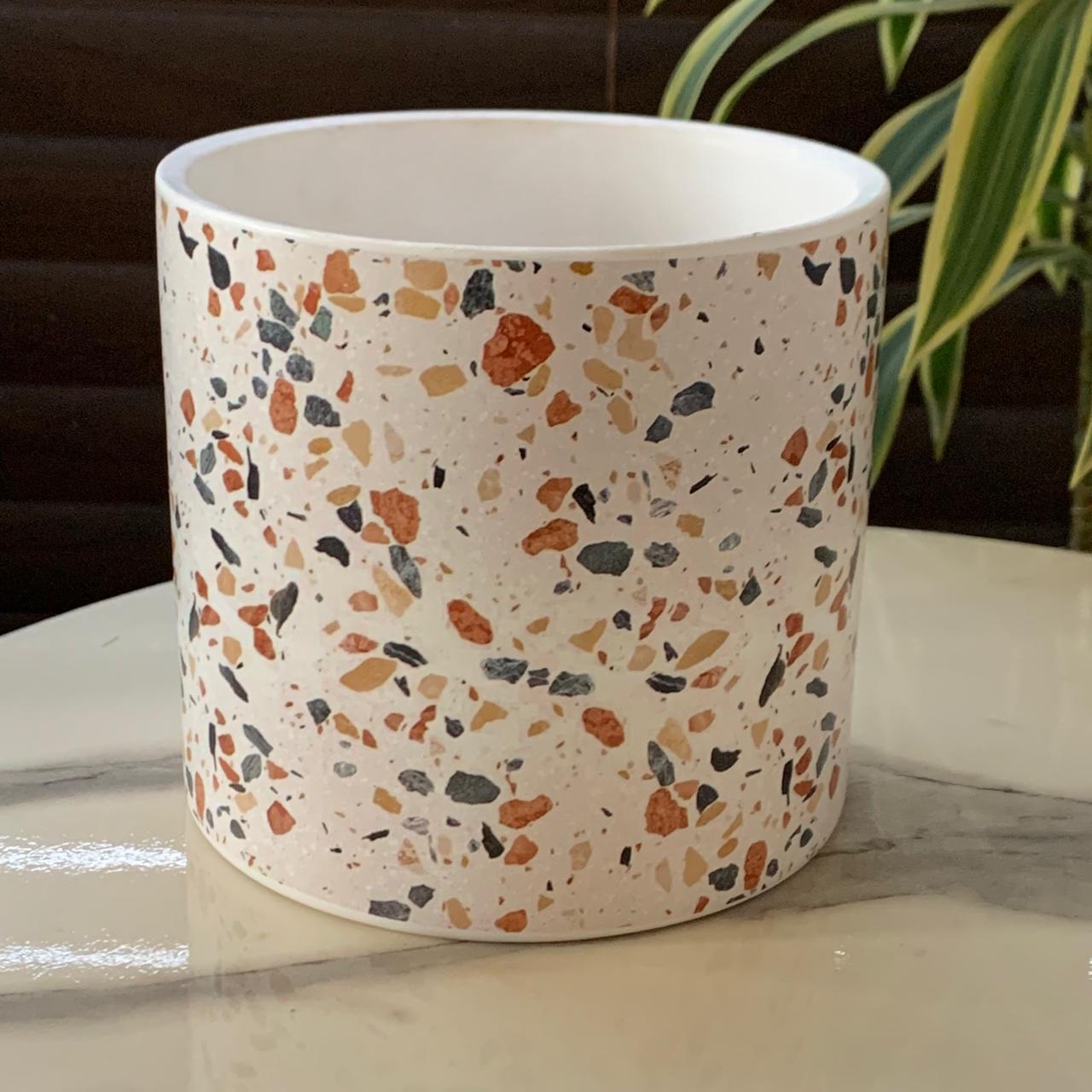 a white round container with multicolored speckled on it
